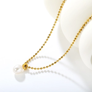 Elegant freshwater pearl pendant necklace on a gold bead chain with minimalist backdrop