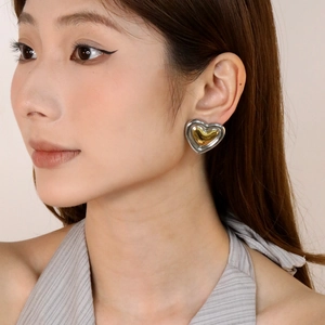 Boucles d'oreilles cœur bicolores or et argent portées par un mannequin style élégant