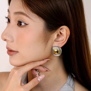 Gros plan de boucles d'oreilles carrées bicolores élégantes portées par un mannequin