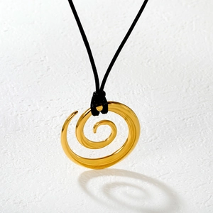 Golden spiral oval pendant necklace with black cord on textured white background