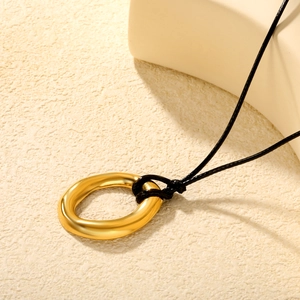 Minimalist irregular gold oval ring pendant necklace with black wax cord on textured stone