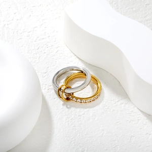 Detailed view of connected silver ring and gold pavé diamond ring with small clasp link