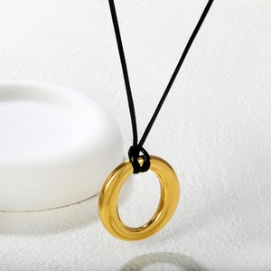 Minimalist stainless steel golden ring pendant with black wax cord on a white background