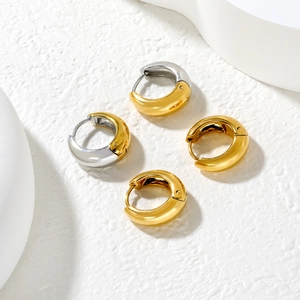 Detail of C-shaped hoop earrings in gold and two-tone silver finish on white stone