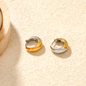 Detail of mixed-metal C-shape earrings with polished gold and silver mirror finish