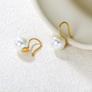 Detail of elegant 10mm white pearl earrings with minimalist matte gold hooks on stone