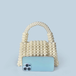 Mini pearl woven handbag in cream white shown next to a smartphone for size reference