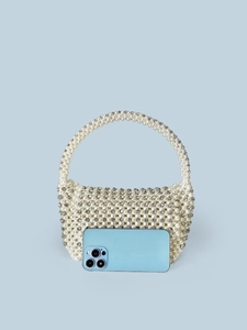 Handmade pearl woven handbag with rhinestones and top handle on light blue background