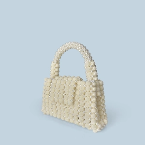Detailed view of handmade white pearl woven texture and elegant flap handle bag