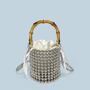 Detail of silver beaded bucket bag featuring bamboo handle and satin drawstring pouch