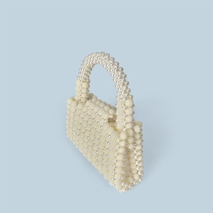 Detailed view of handmade cream pearl woven handbag with beaded handle and flap closure