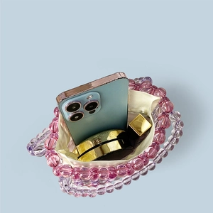 Detailed view of pink beaded tote bag interior holding a smartphone and cosmetics