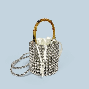 Detail of silver beaded bucket bag featuring a faux bamboo handle and satin drawstring