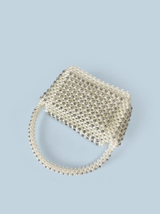 Macro view of handmade pearl evening bag featuring sparkling rhinestones and woven texture