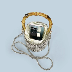 Detail of silver beaded bucket bag featuring bamboo handle and satin drawstring lining