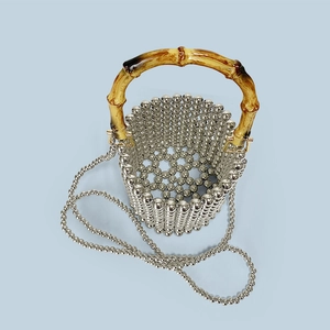 Detailed view of silver bead woven bucket bag with natural bamboo handle and pearl chain
