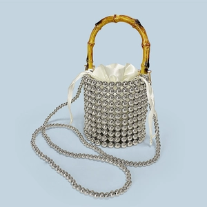 Detail of silver beaded bucket bag featuring a natural bamboo handle and satin drawstring pouch
