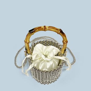 Detail of silver beaded bucket bag featuring bamboo handle and satin drawstring pouch