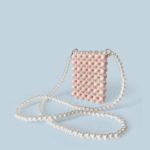 Detail of pink and white pearl woven pattern on a crossbody mini bag with gold hardware