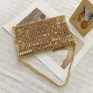 Detailed macro shot of shimmering golden paillette beads and delicate chain on luxury clutch