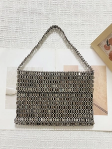 Detailed view of silver oval metallic beads and woven texture on a luxury handbag