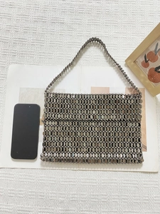 Close-up of metallic beaded handbag with smartphone for scale on white waffle fabric