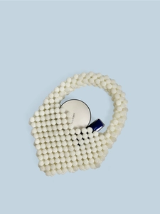 Handmade beige beaded heart handbag with interior showing cosmetic storage capacity