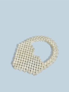 Macro detail of beige beaded heart handbag with intricate hand-woven pearl texture