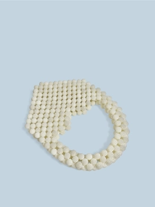 Close-up of handmade white pearl beaded handbag with heart-shaped weaving texture