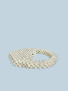 Detailed view of woven beige beaded handbag featuring textured spherical pearl patterns