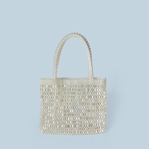 Close-up of handmade cream pearl beaded handbag with woven texture and top handle