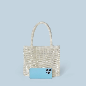 Mini pearl beaded tote bag with handles shown next to a smartphone for size reference