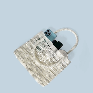 Detail of handmade beaded tote bag showing storage capacity for makeup and phone