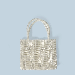 Close-up of white beaded handbag with dual round handles and reflective glossy finish