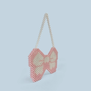 Detail of pink and white beaded handbag featuring a unique handmade bow-shaped design