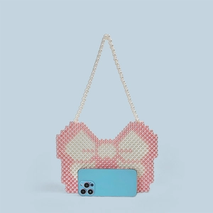Detailed view of pink and white beaded y2k butterfly bag with smartphone for scale