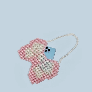 Detail view of the pink and white beaded heart bag holding a smartphone for size reference