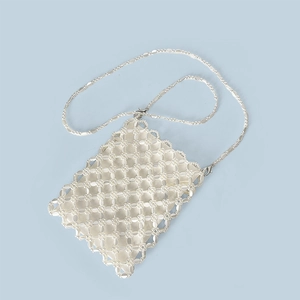 Dettaglio della borsa a tracolla in perle fatta a mano con catena d'argento su sfondo blu