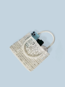 Handmade pearl beaded tote bag showing storage capacity with phone and cosmetics