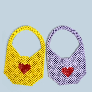 Detailed top view of handmade acrylic beaded bags in yellow and lavender with red hearts
