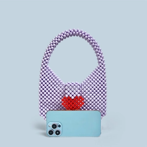 Detail of beaded handbag with red heart pattern and phone for size comparison