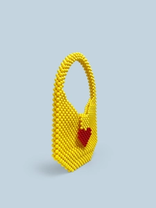 Detail of yellow acrylic beaded handbag with red woven heart and glossy resin texture