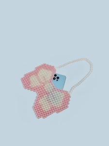 Handmade pink and white beaded heart bag with pearl handle holding a smartphone