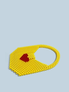 Detail of hand-woven yellow beaded tote bag with a distinctive red heart pattern