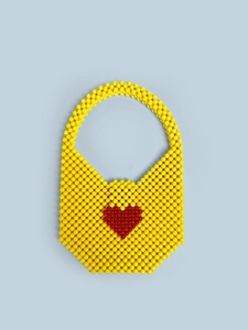 Detail of handmade yellow acrylic beaded handbag featuring a red heart pattern