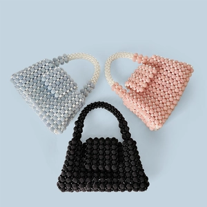 Detailed overhead shot showing three handmade beaded handbags in blue, pink, and black