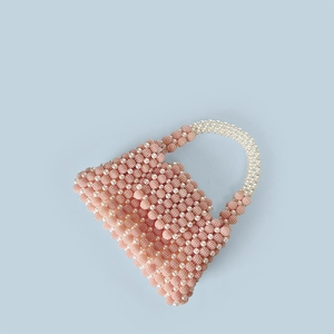 Macro detail of handmade pink beaded handbag with elegant white faux pearl handles