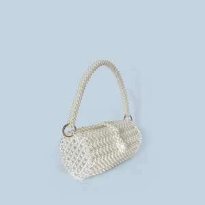 Detail of handcrafted white pearl cylindrical bag with elegant gold metal rings