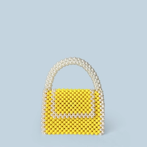 Detail of yellow handmade beaded handbag featuring pearl-white beads and handle texture