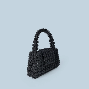 Detail of handmade black beaded handbag showing intricate woven texture and round handle